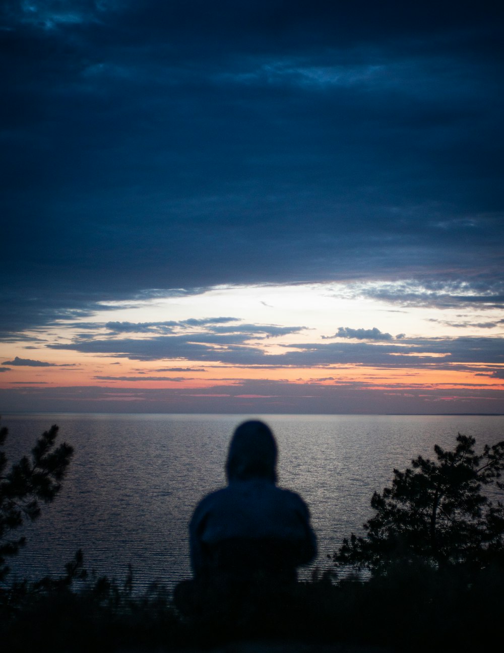 a person sitting on a bench watching the sunset