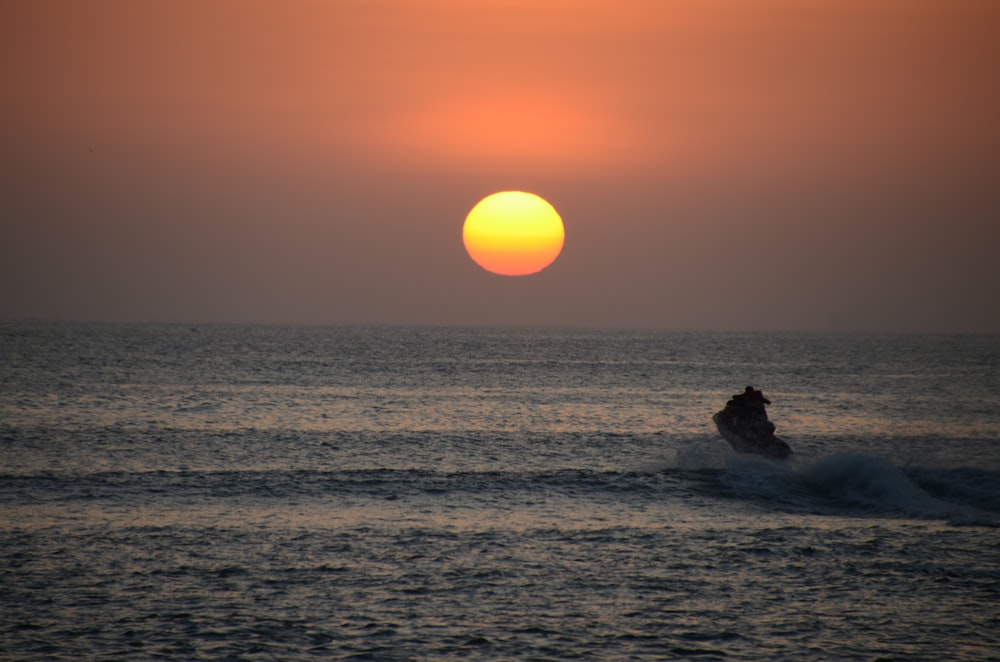 a person riding a surfboard in the ocean at sunset