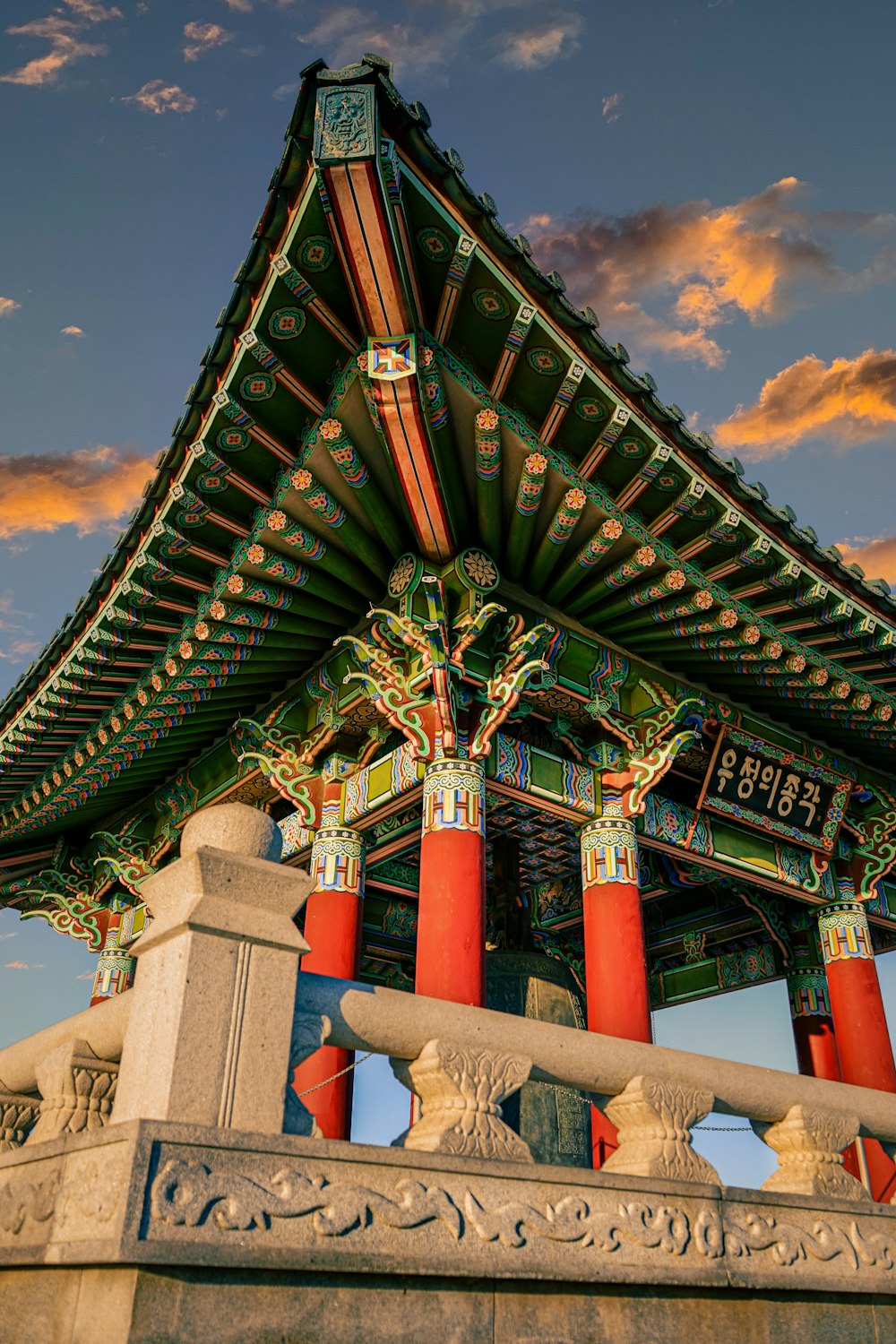 a tall building with red pillars under a cloudy sky