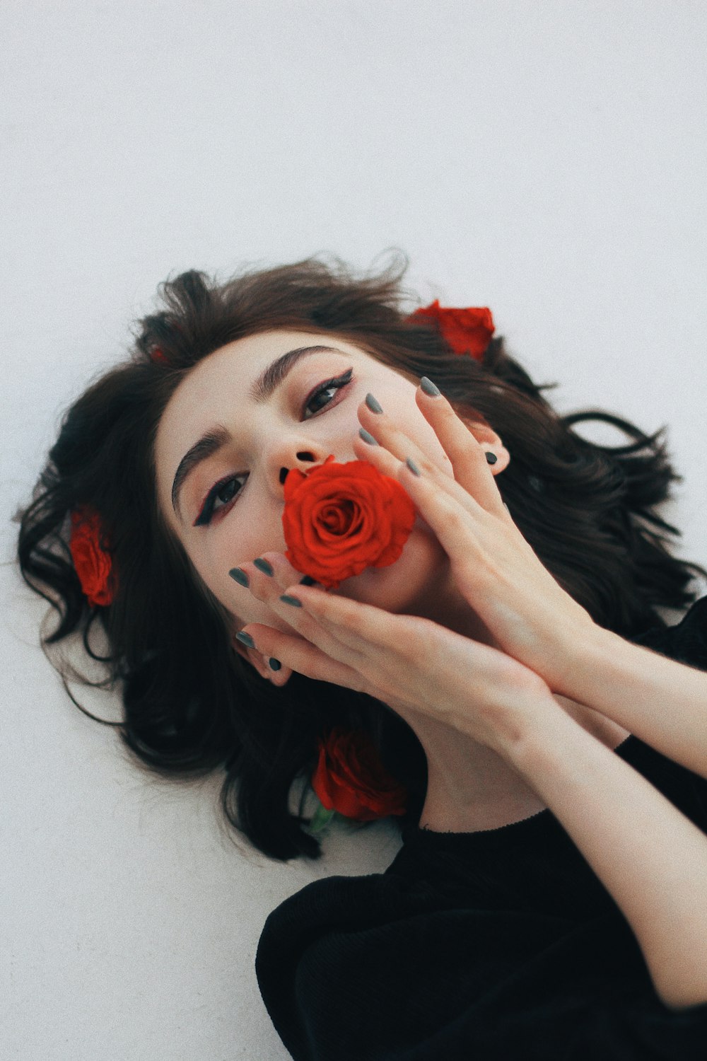 a woman holding a rose up to her face