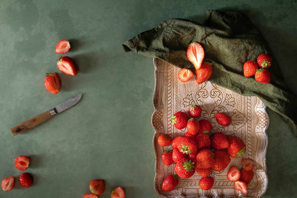a bunch of strawberries sitting on a table next to a knife
