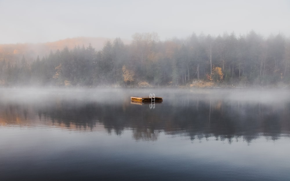 a boat floating on top of a lake next to a forest