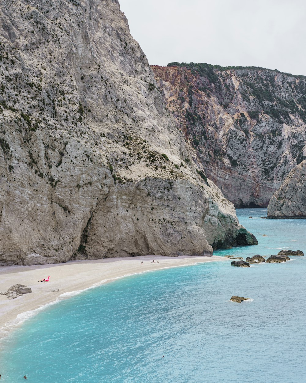 a sandy beach next to a rocky cliff