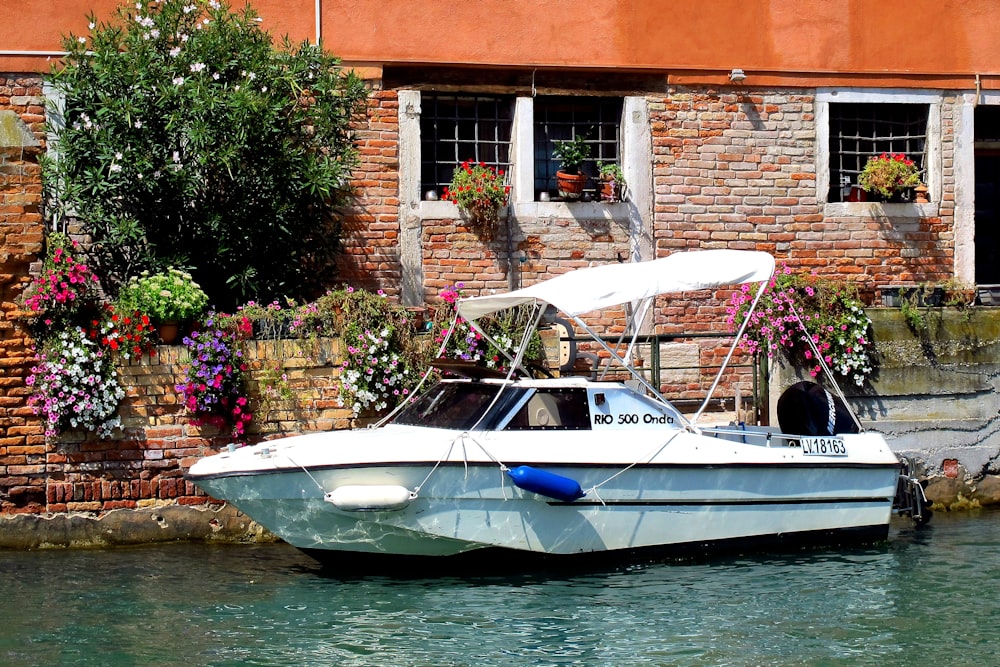 a white boat in a body of water next to a brick building