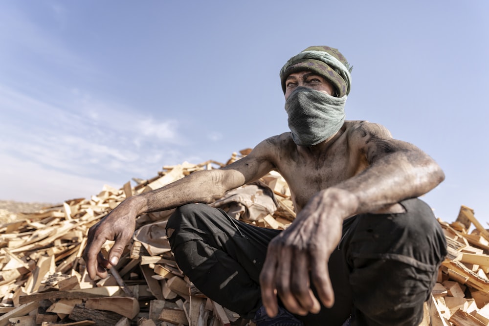 a man sitting on top of a pile of wood