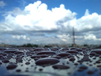 A close-up of a sensor device analyzing raindrops with a blurred cityscape in the background.