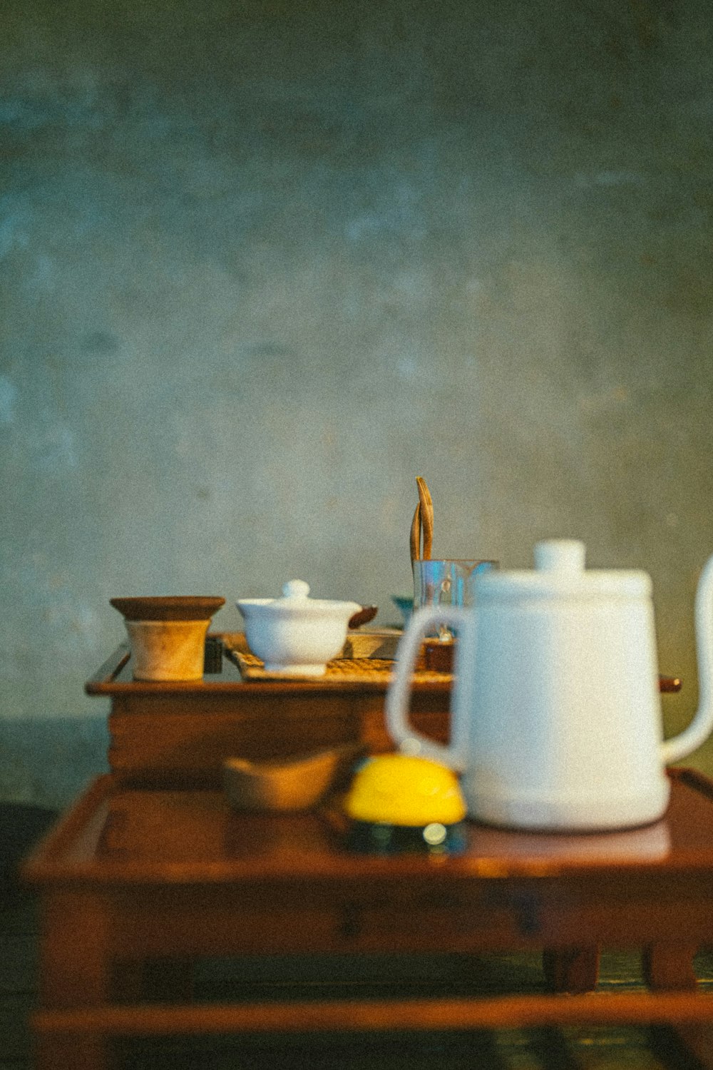 a wooden table topped with a white tea pot