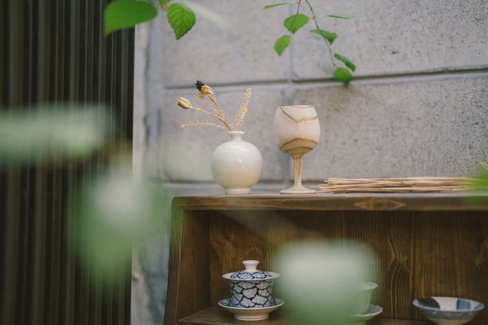 a table with two vases and a plant on top of it