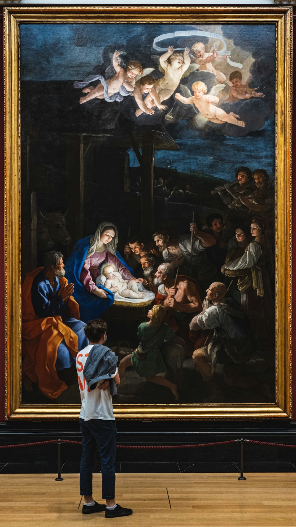 a young boy standing in front of a painting of the birth of jesus