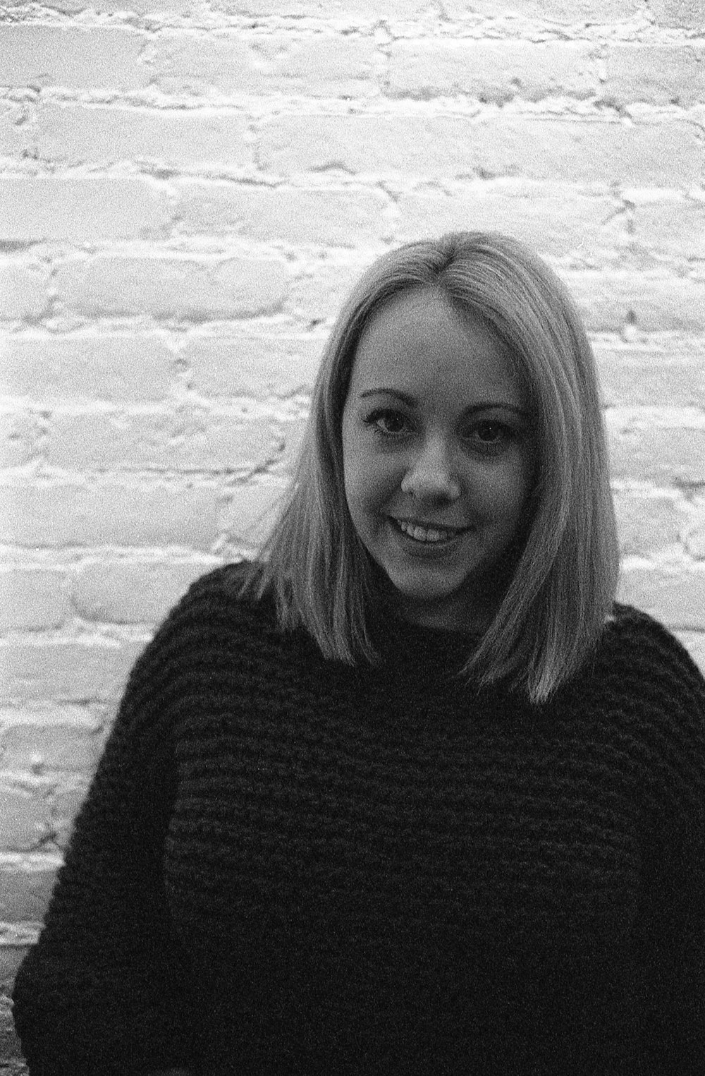 a woman standing in front of a brick wall