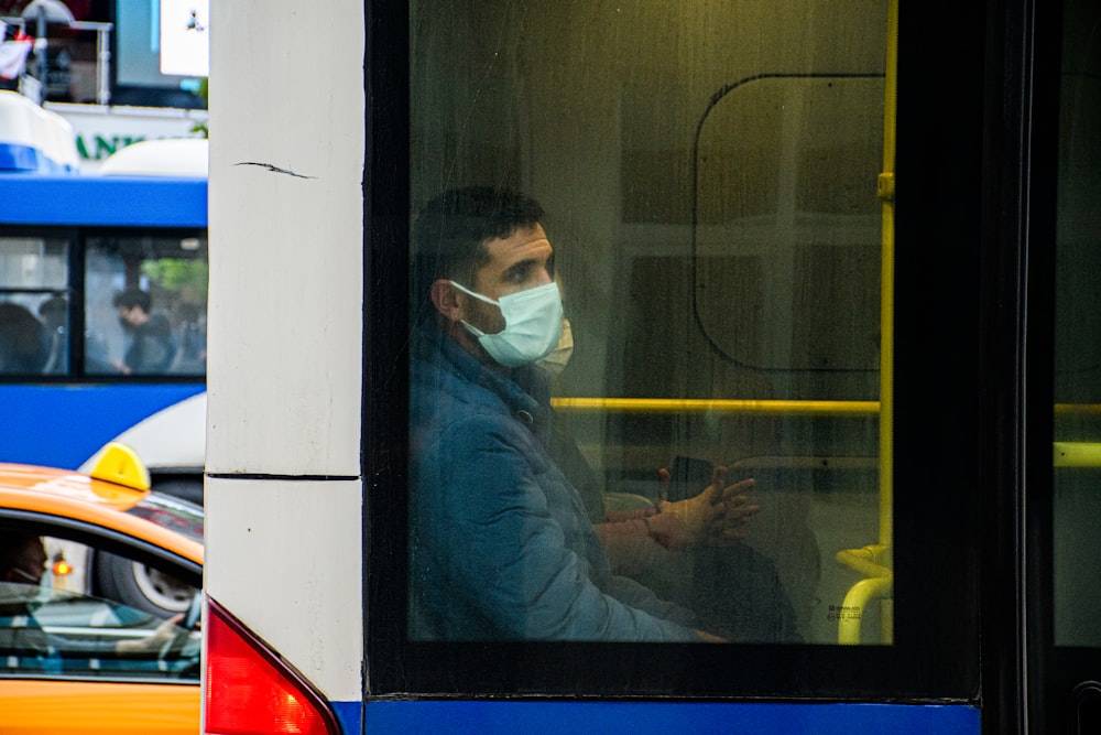 a man wearing a face mask sitting on a bus