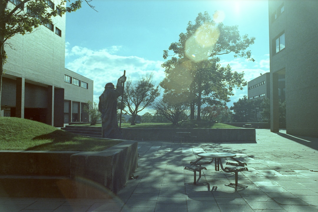 a statue of a person standing in front of a building, UMass Boston Campus. Nikon FE2 + Kodak Ektachrome 100 cross-proces