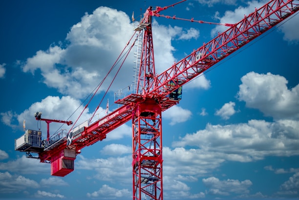 a large red crane sitting on top of a sandy beach