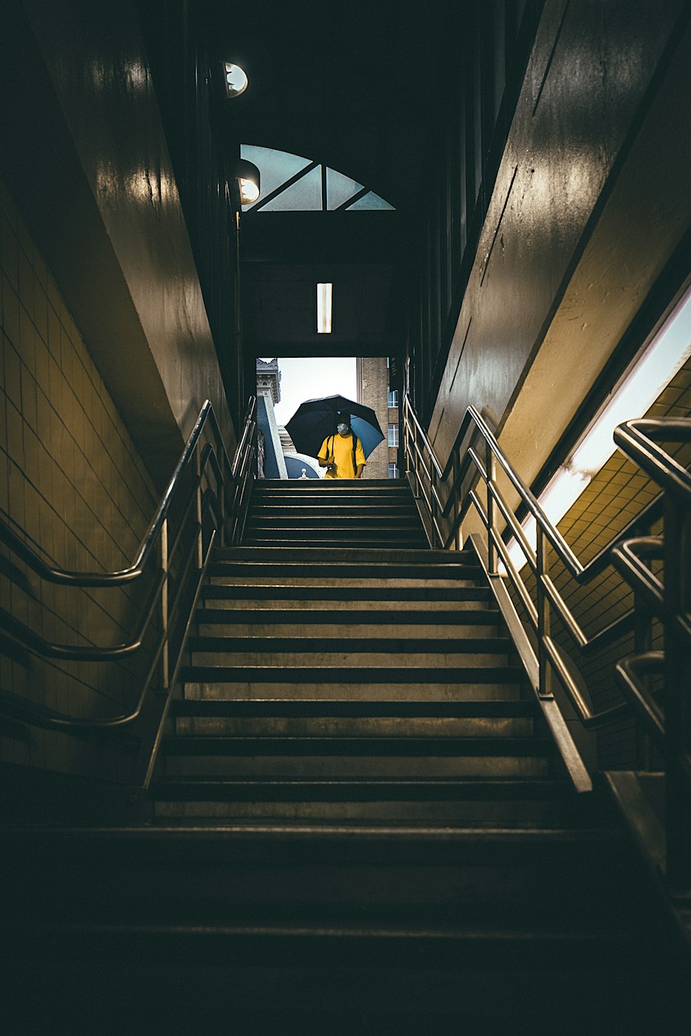 a person with an umbrella walking down a flight of stairs