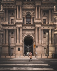 a man walking across a street in front of a large building