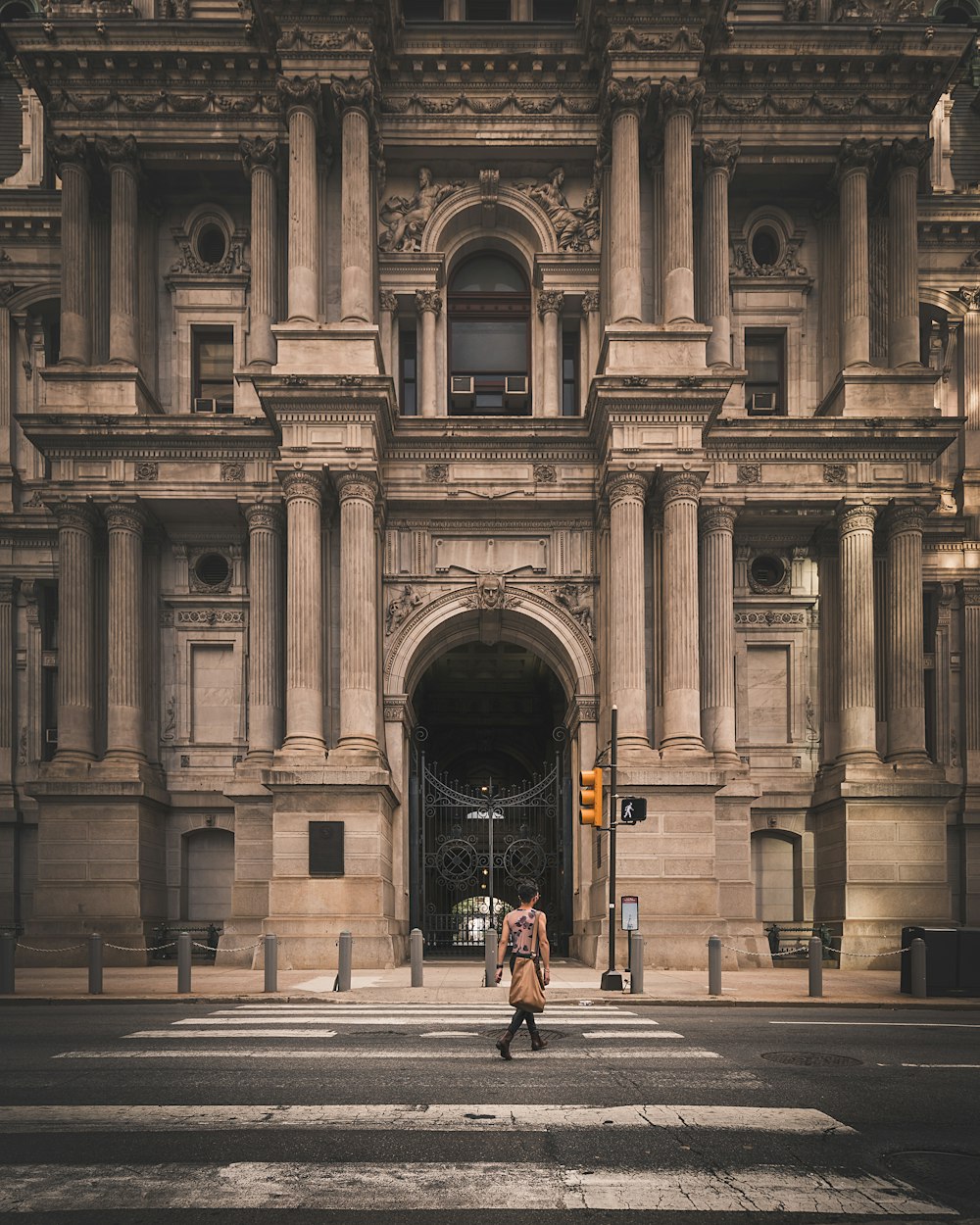 a man walking across a street in front of a large building