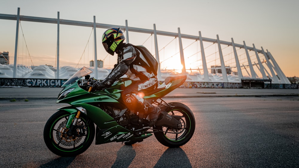 uma pessoa que monta uma motocicleta verde em uma rua