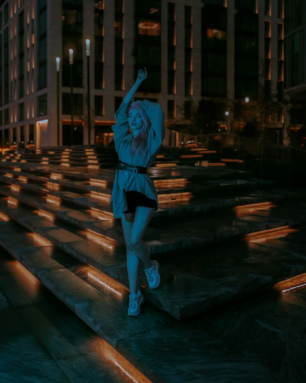 a woman standing on steps in a city at night