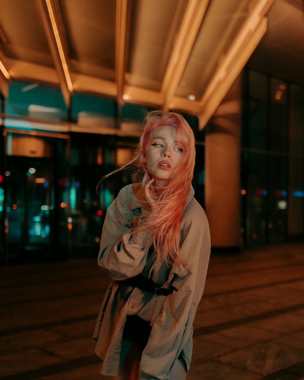 a woman with pink hair standing on a sidewalk