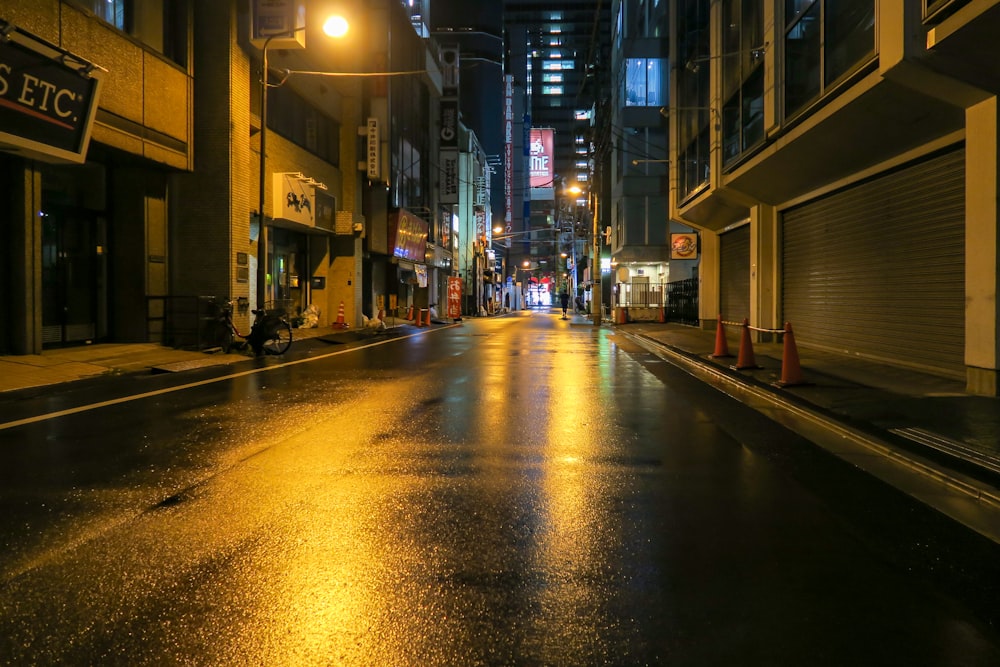a city street at night with a wet sidewalk