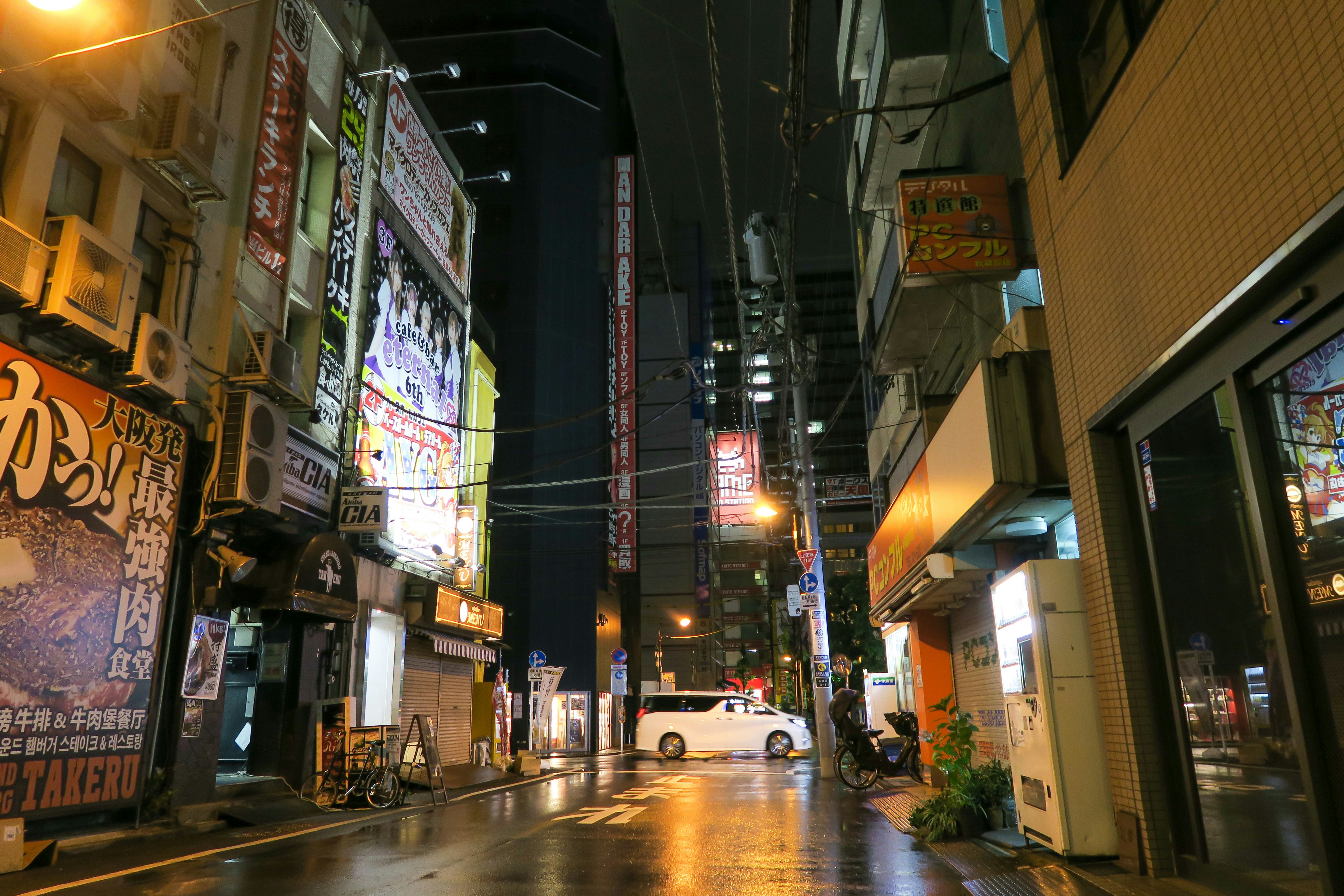 Eine Stadtstraße in der Nacht mit einem Auto, das am Straßenrand geparkt ist