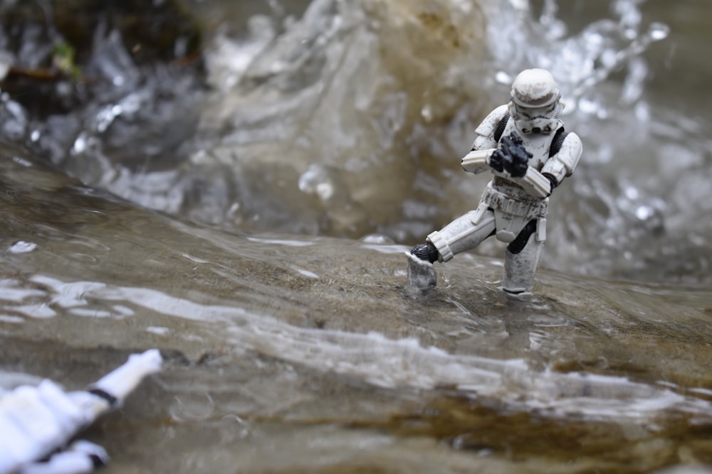 a toy astronaut walking through a stream of water