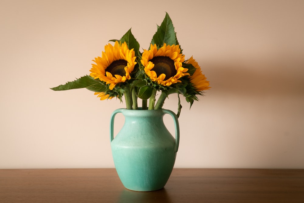 a vase with three sunflowers in it on a table