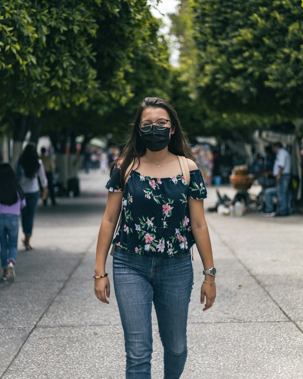 a woman wearing a mask walking down a sidewalk