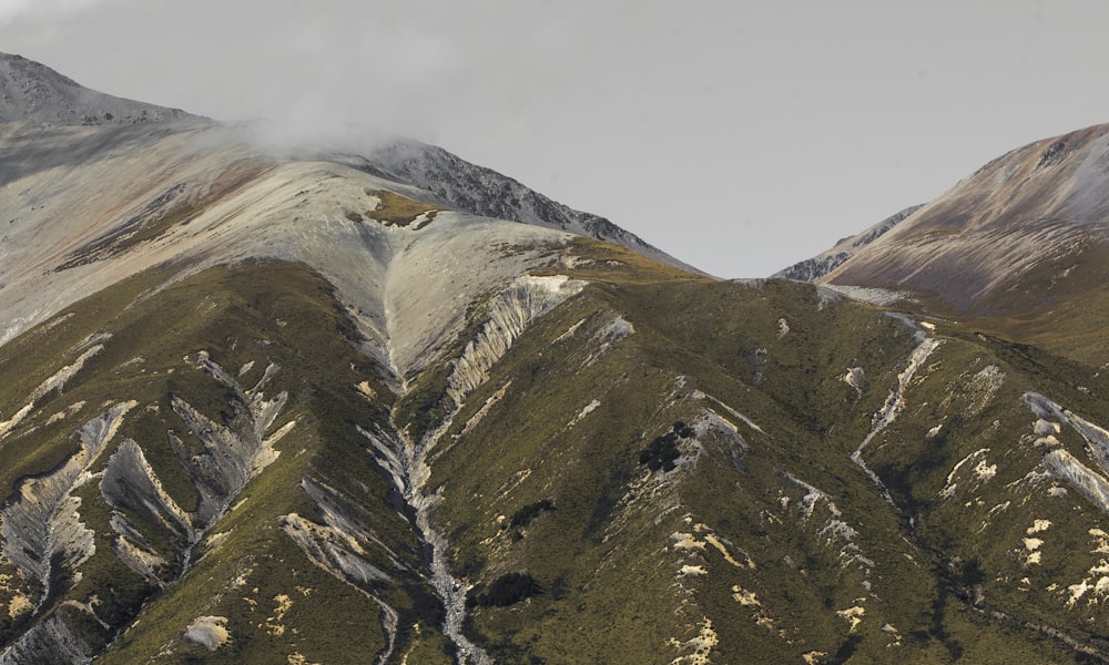 a group of mountains covered in snow and green grass