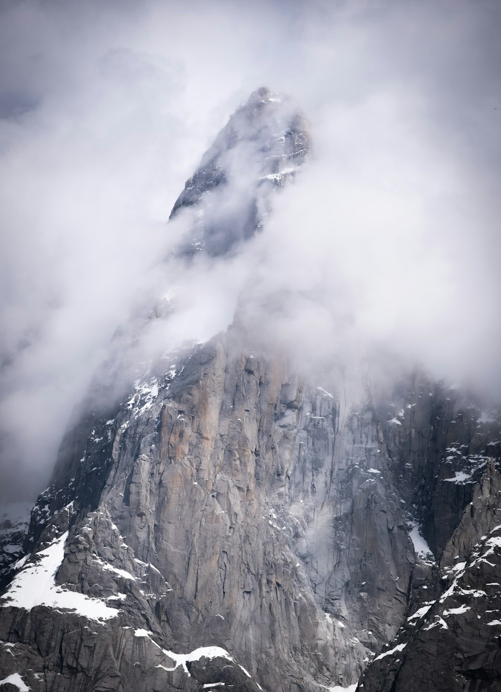 a very tall mountain covered in snow and clouds