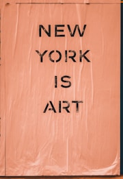 A textured poster features the bold black text 'NEW YORK IS ART' on a peach-colored wrinkled backdrop.