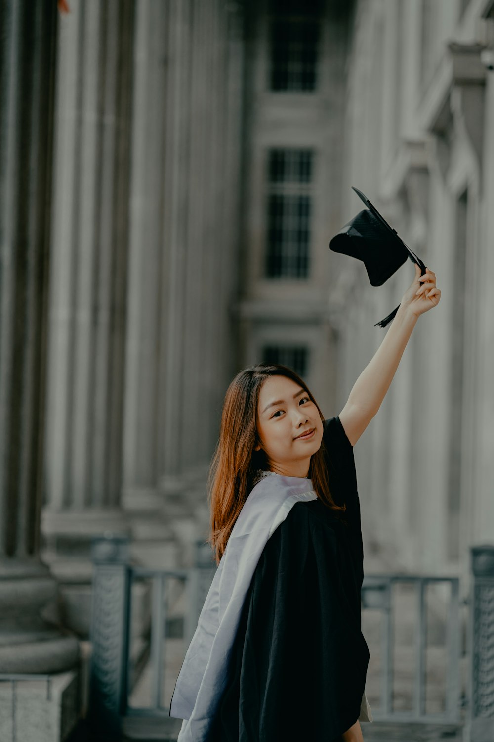 a woman holding a graduation cap in the air