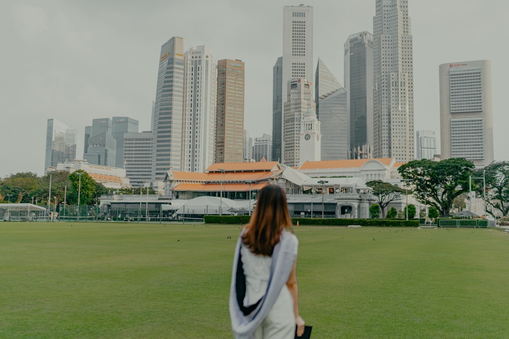 a woman standing in a field with a city in the background