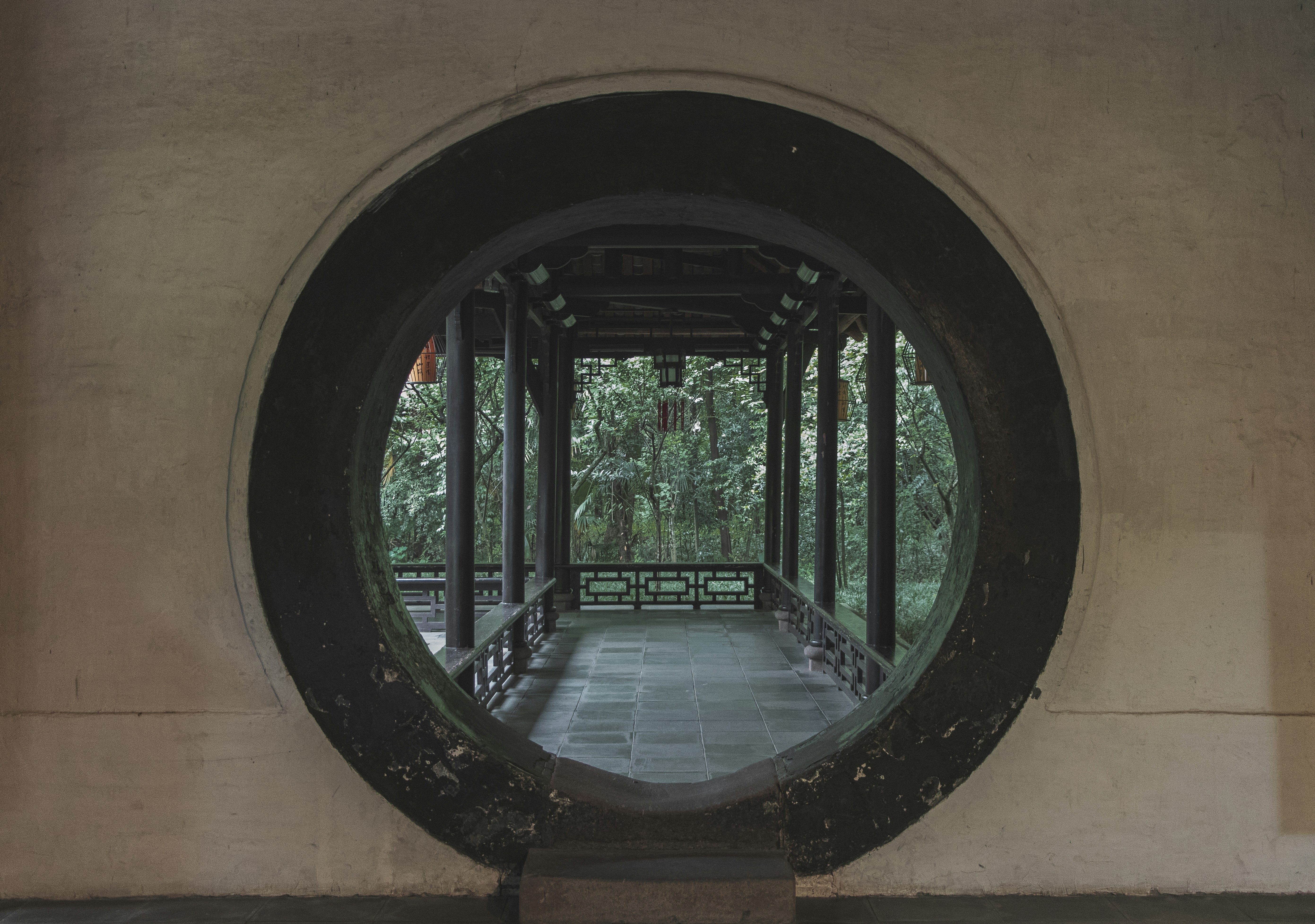 a circular window in a wall with a walkway in the background