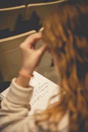 a woman sitting at a table writing on a piece of paper