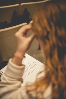 a woman sitting at a table writing on a piece of paper