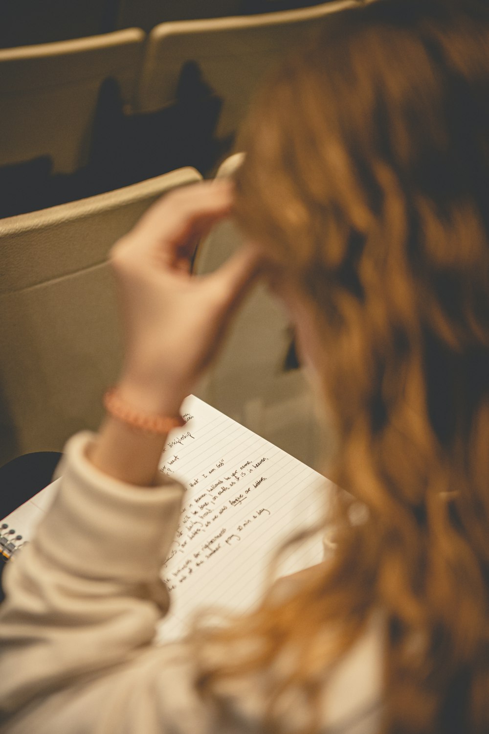 a woman sitting at a table writing on a piece of paper