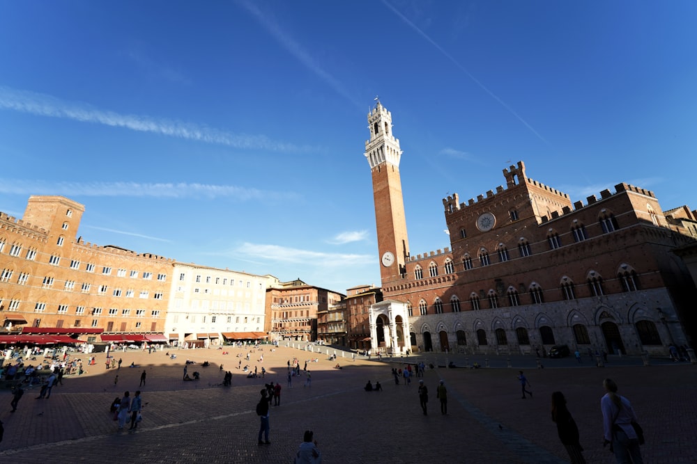 people walking on street near brown concrete building under blue sky during daytime