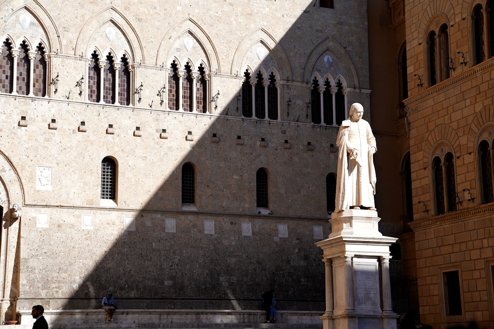 white statue in front of gray concrete building