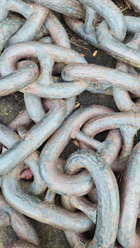 A close-up of broken chains lying on a dark surface with a warm golden light shining through.