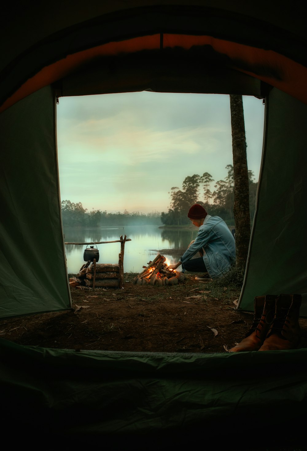 man in white dress shirt sitting on camping chair near bonfire during daytime