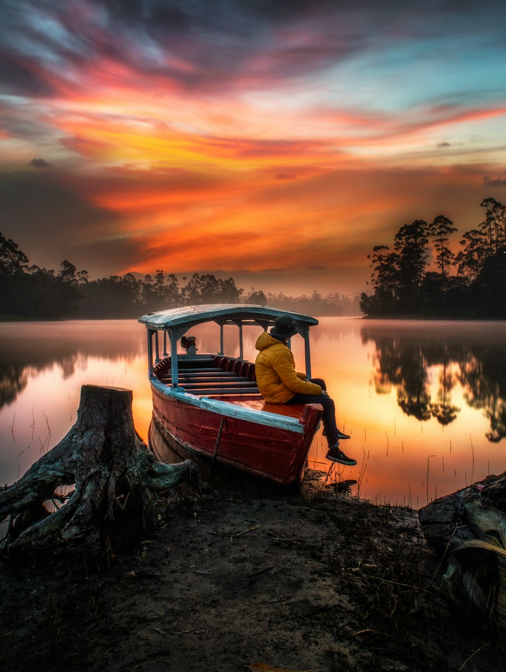 Mann im roten Hemd sitzt bei Sonnenuntergang auf dem Boot