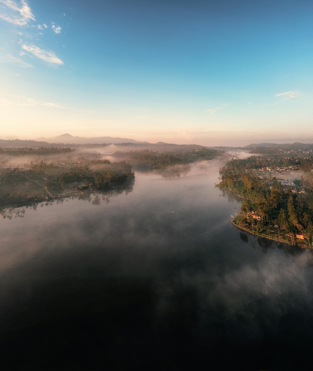 árvores verdes ao lado do lago sob o céu azul durante o dia