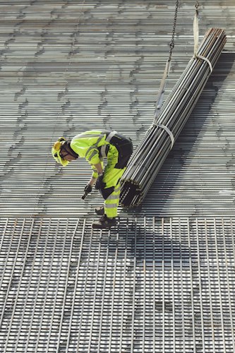 Construction worker wearing a hard hat and safety vest reviewing plans on a tablet at a job site