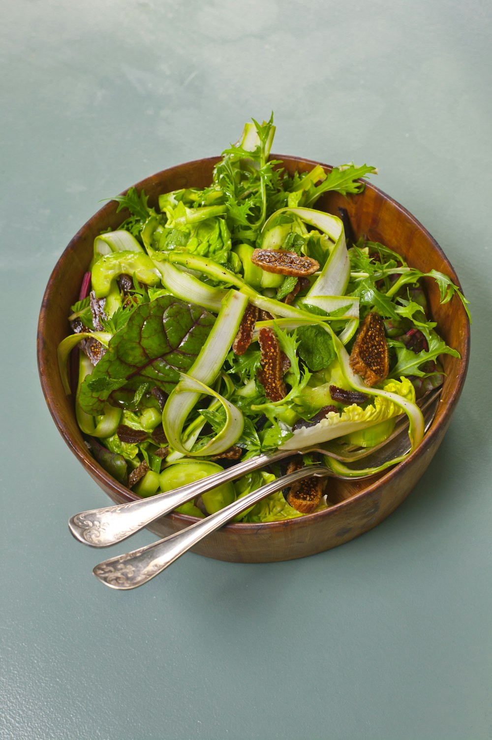 a wooden bowl filled with a salad and two spoons