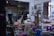 An art studio filled with easels, stools, and various painting supplies. The walls display sketches and busts, creating an atmosphere of creativity and learning. A tripod and several colorful plastic stools are scattered across the room. A large window with a curtain lets in natural light.
