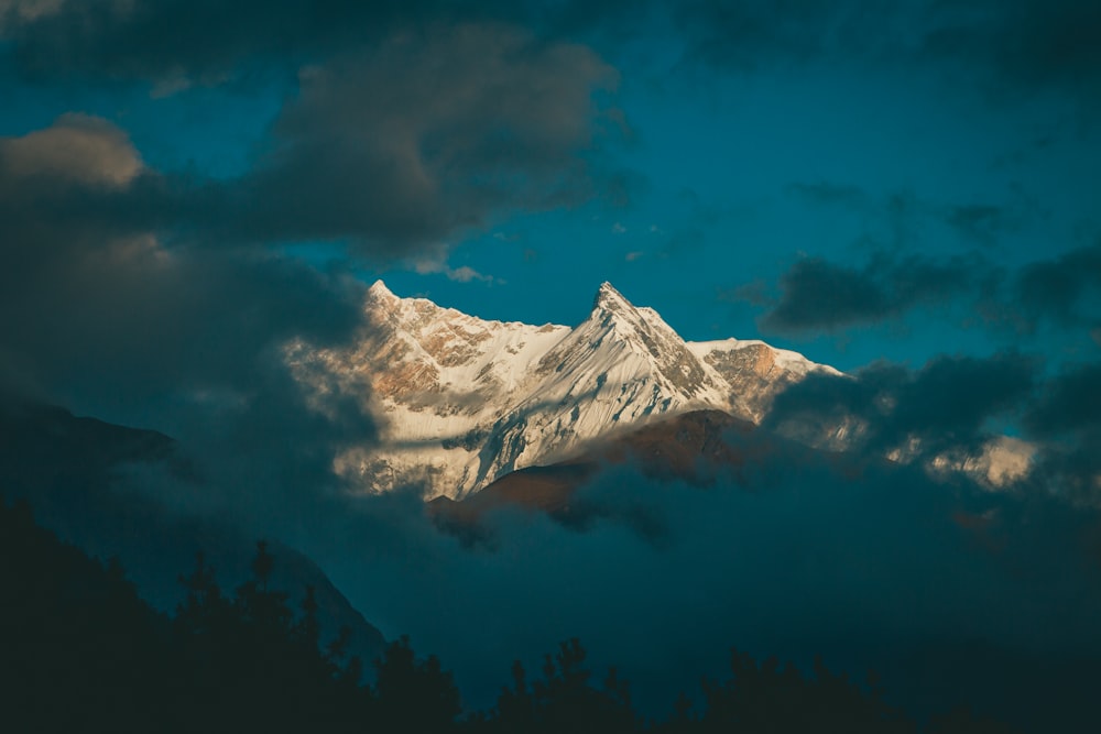 a snow covered mountain is seen through the clouds