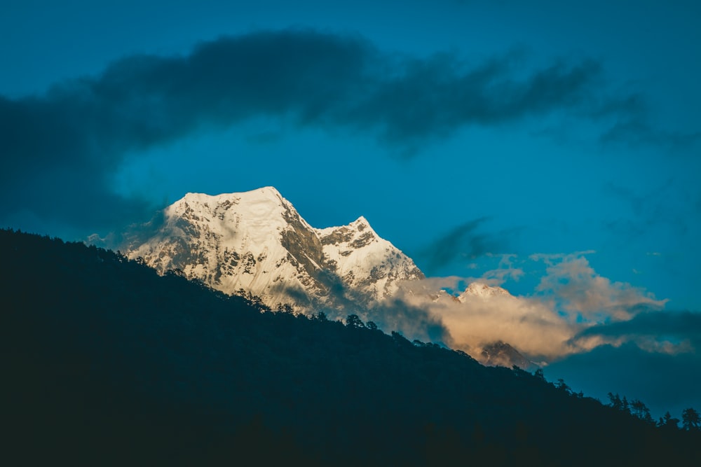 a snow covered mountain under a cloudy sky