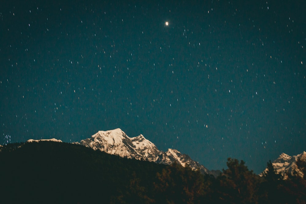 the night sky with stars above a mountain range