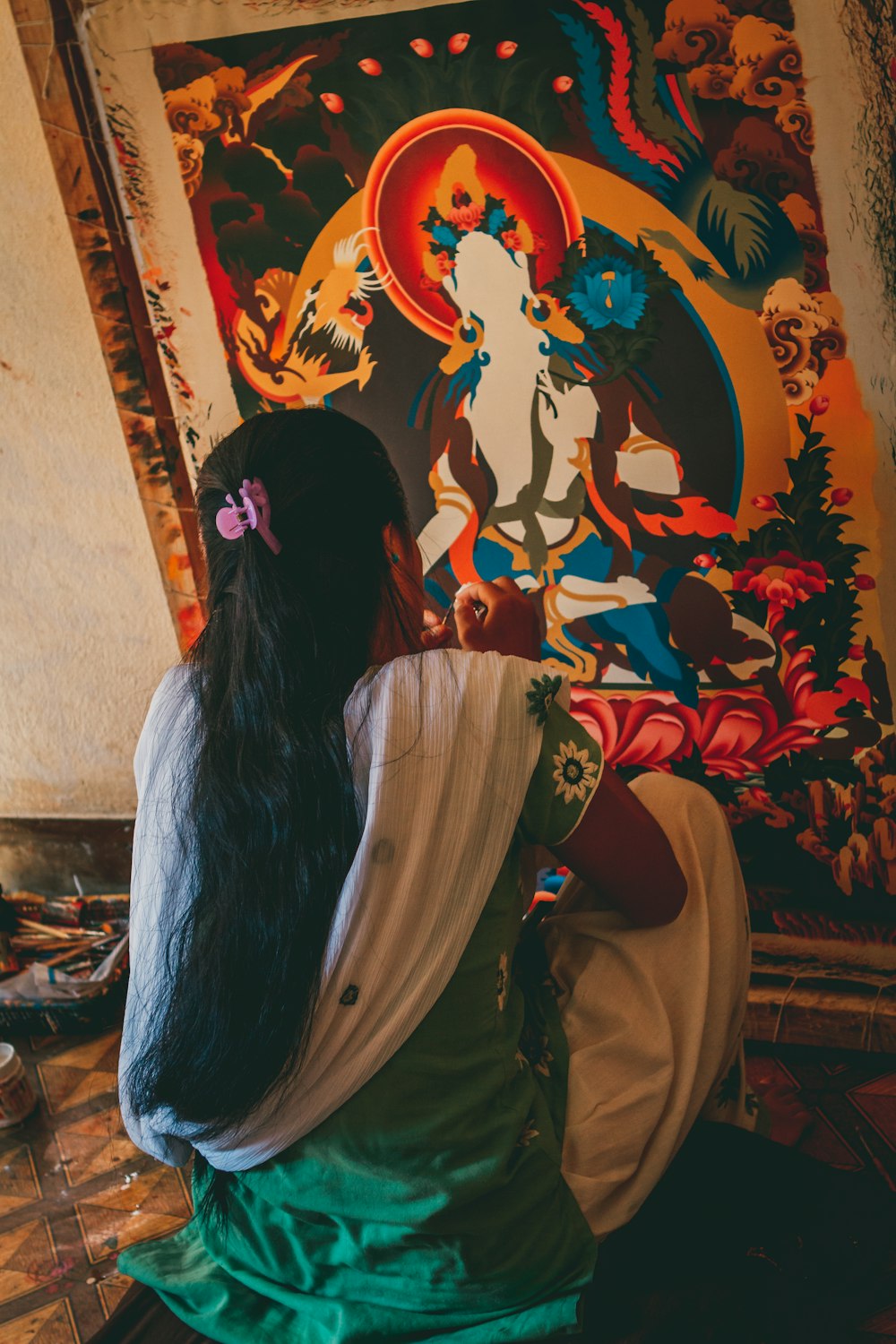 a woman sitting on the ground in front of a painting